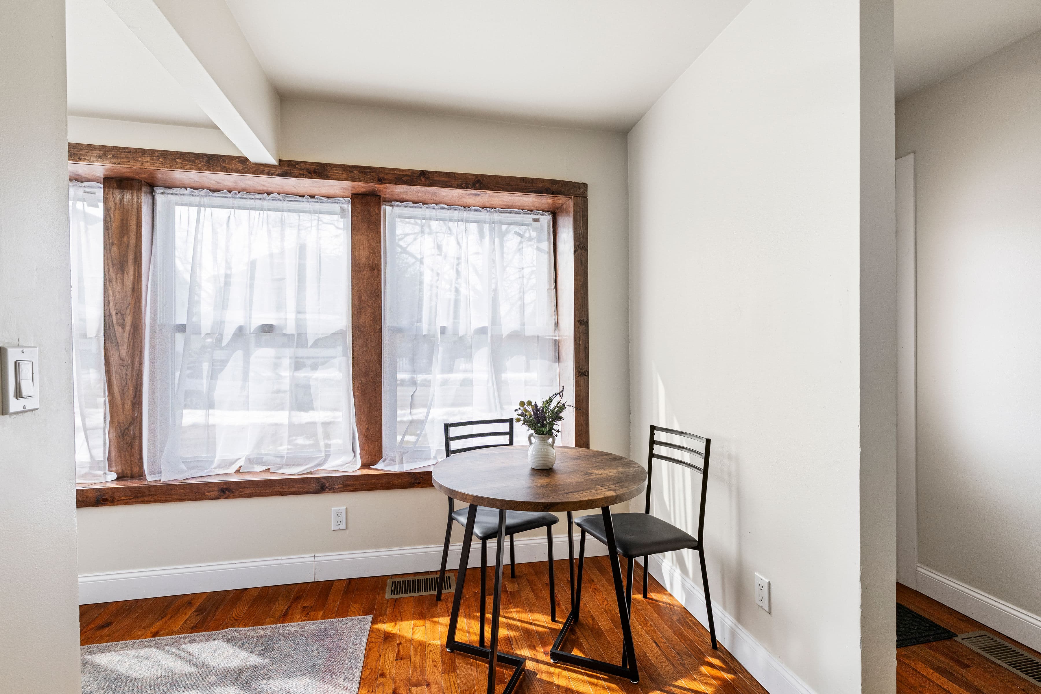 A bistro table beside the wood-trimmed windows